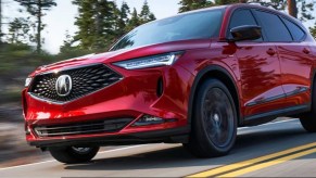 A red 2022 Acura MDX races down a wooded road.