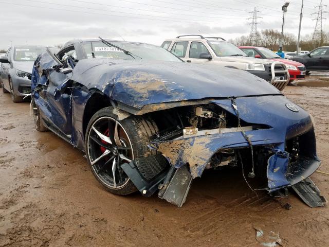 An image of a damaged Toyota Supra in an open lot.