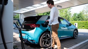 A man plugs a charging cable into the filler neck of a VW ID.3 during a press tour of a charging park for electric cars outside Volkswagen's Transparent Factory.