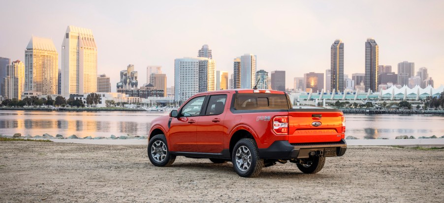 an orange ford maverick parked on the beach with a skyline background