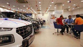 A group of people discuss lease options in a dealership at a round table