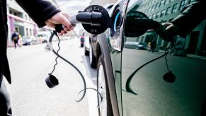 A person plugs an EV charger into a green car