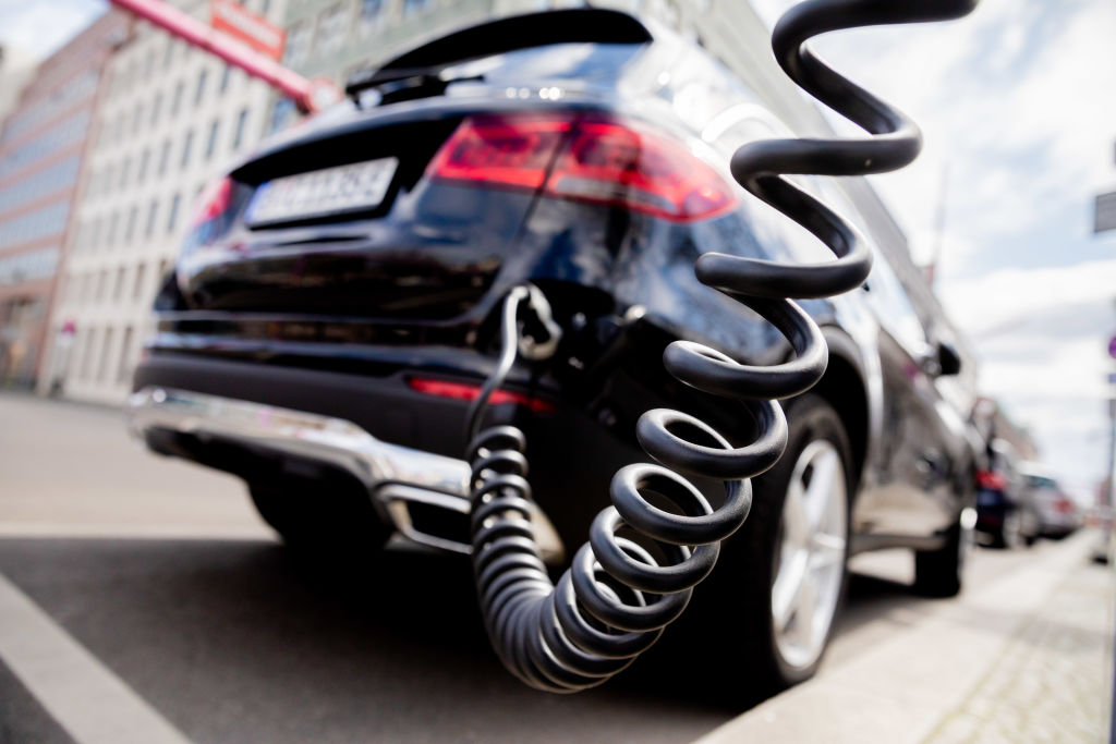 A black Mercedes SUV plugged in to an EV charger