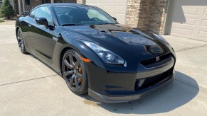 A black modified 2010 Nissan GT-R Premium in front of a tan home