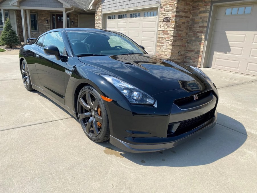 A black modified 2010 Nissan GT-R Premium in front of a tan home