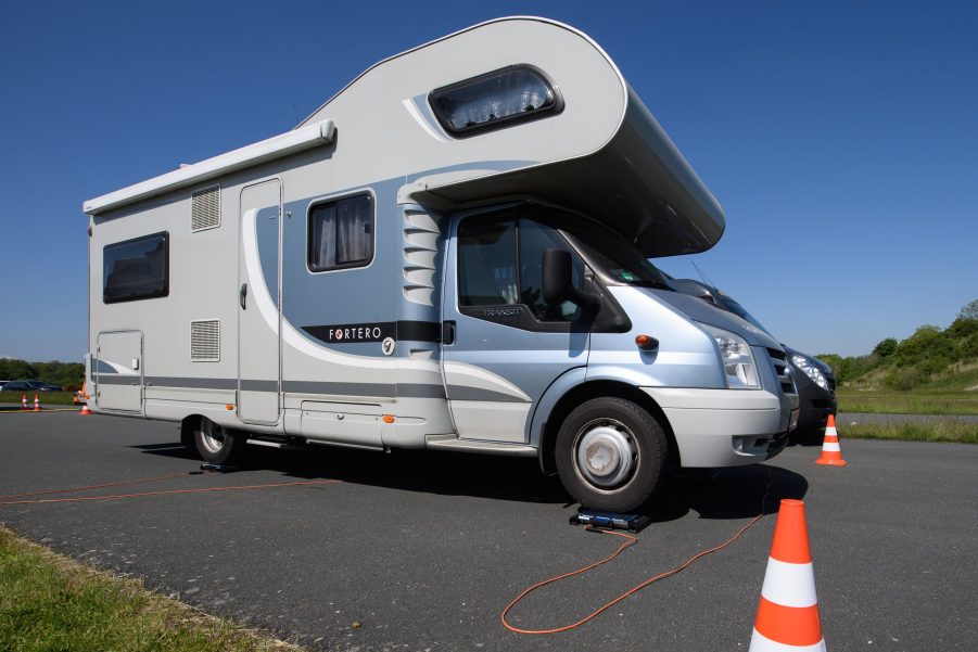 A motorhome RV stands with its wheels on a scale of the ADAC.