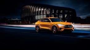 An orange 2021 Ford Mustang Mach-E racing through a city.