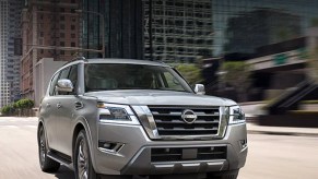 A silver 2021 Nissan Armada drives through a city.