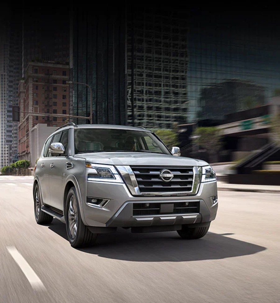 A silver 2021 Nissan Armada drives through a city.