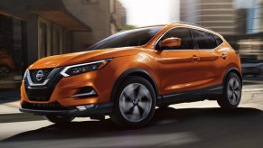 An orange 2021 Nissan Rogue Sport driving through a city.