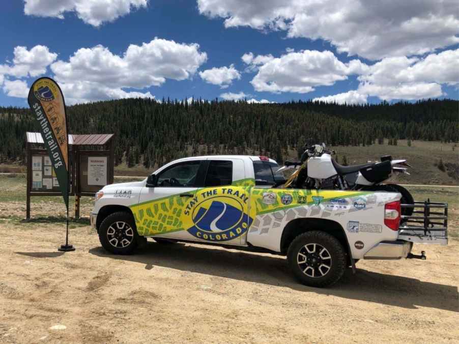 The Stay the Trail truck and dirt bike parked in the dirt to help ATV and dirt bikers learn the OHV rules