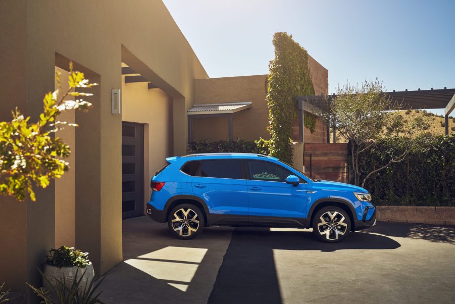 The blue 2022 Volkswagen Taos parked in front of a drive way on a sunny day