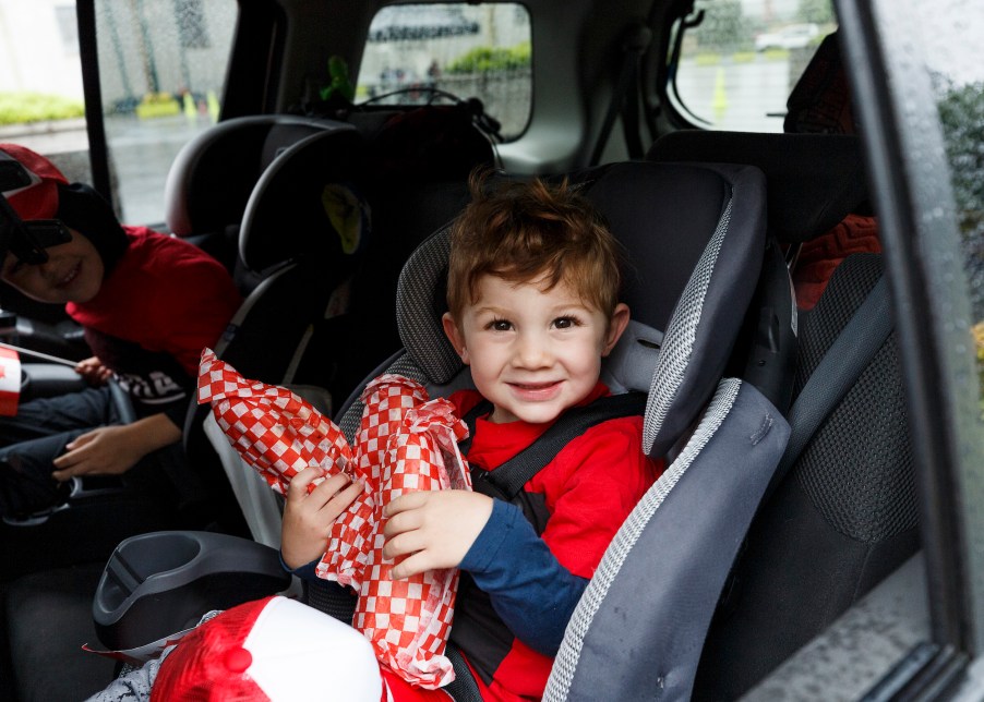 Two children in car sats in the back of a vehicle