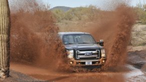 A diesel pickup truck splashes through a mud puddle