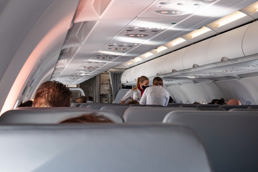 Flight attendants wearing facemasks serve passengers during a flight in October 2020