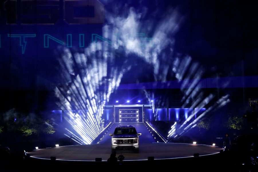 A silver Ford F-150 electric pickup truck on display in front of theatrical lighting