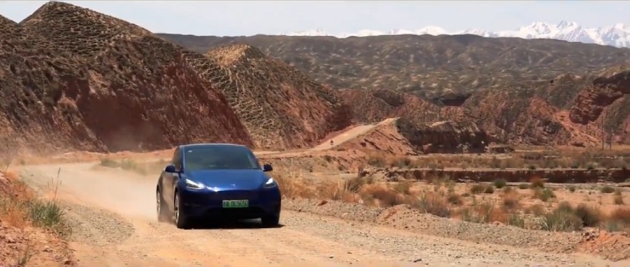 A dark blue Tesla drives through the mountains of China.