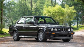 A black 1991 BMW 325iX on a tree-lined road