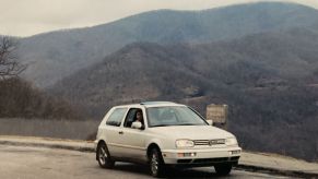 A 1995 Volkswagen Golf GTI model parked near grassy hills