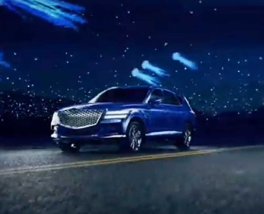 A blue 2021 Genesis GV80 against a dark night sky.