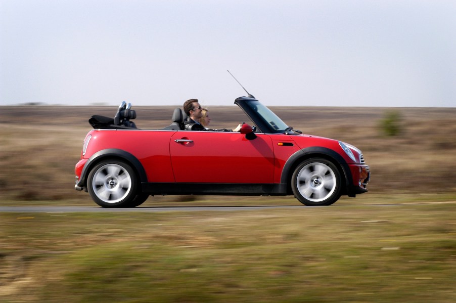 A red 2004 Mini Cooper convertible travels on a country road