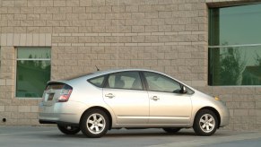 A silver 2004 Toyota Prius hybrid car parked next to a beige brick building