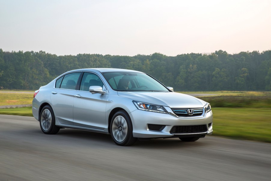 A silver 2015 Honda Accord Hybrid EX-L driving, the 2015 Honda Accord Hybrid is the best used hybrid under $20,000