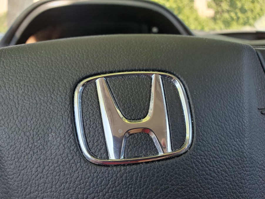 Close-up of a silver Honda logo on a black CR-V steering wheel