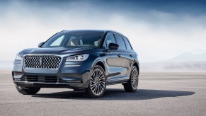 A bluish-gray 2020 Lincoln Corsair luxury compact SUV parked on asphalt in front of mist and mountains