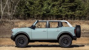 A four-door 2021 Ford Bronco model parked on a dirt plain near a forest