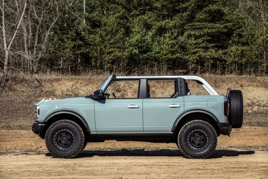 A four-door 2021 Ford Bronco model parked on a dirt plain near a forest