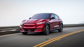 A red 2021 Ford Mustang Mach-E driving on a highway