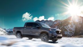 The 2021 Honda Ridgeline RTL-E pickup truck model driving across a snowy plain as the sun rises over a mountain