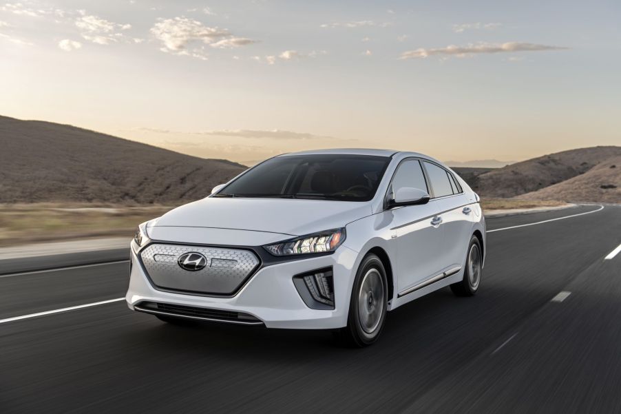 A white 2021 Hyundai Ioniq Electric sedan model driving on a highway