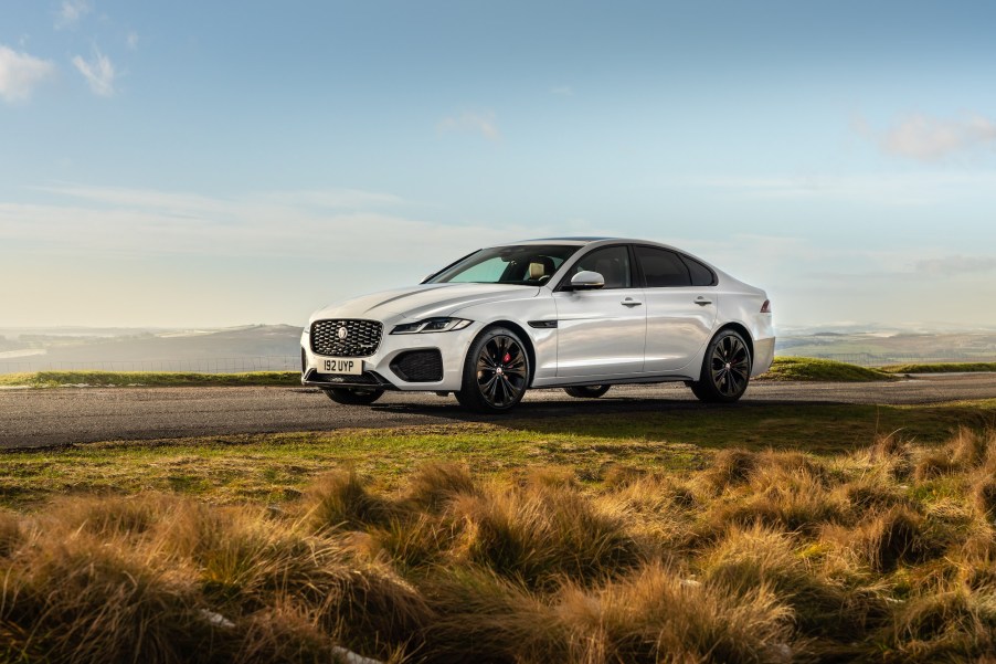 A white 2021 Jaguar XF luxury midsize sedan parked on a road overlooking mountains on a sunny day