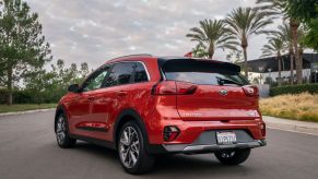 A red 2021 Kia Niro Touring model parked on an asphalt road near palm trees