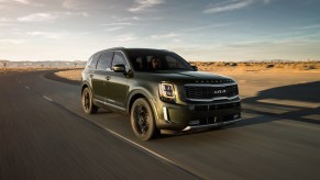 A green 2021 Kia Telluride driving down an empty road, the Telluride is a new three-row SUV