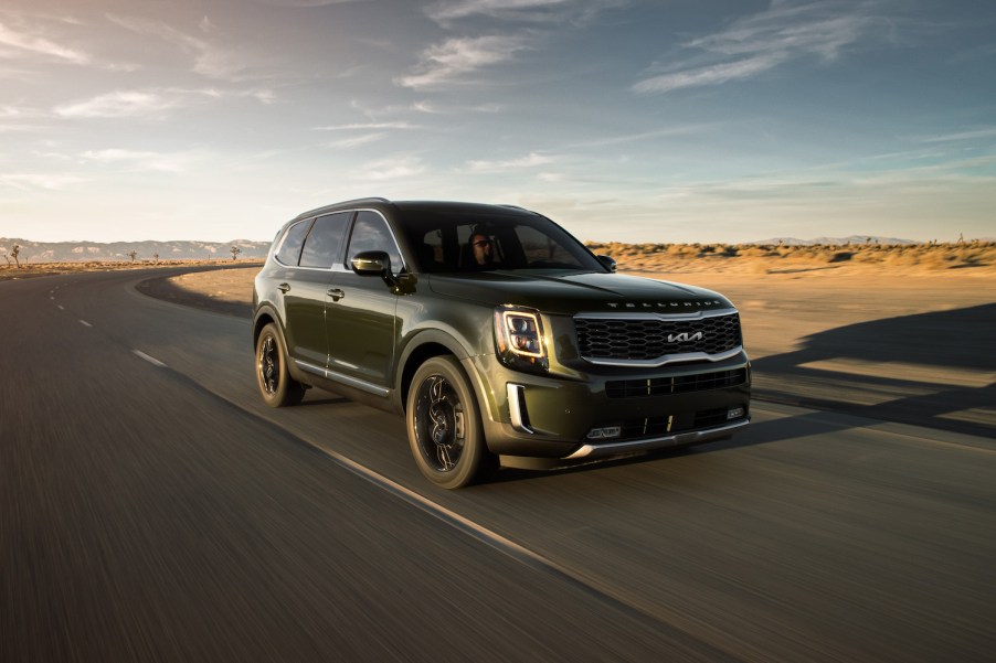 A green 2021 Kia Telluride driving down an empty road, the Telluride is a new three-row SUV