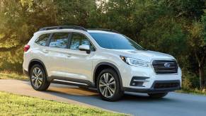 A white 2021 Subaru Ascent SUV parked on a trail near a grass field and forest