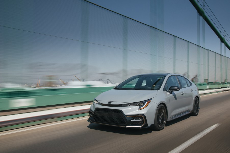 A gray 2021 Toyota Corolla Apex Edition compact car traveling on a bridge alongside a ship port