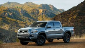 A silver 2021 Toyota Tacoma midsize truck in a desert mountainous area.