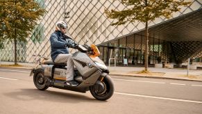 A blue-and-gray-clad rider on a gray-and-orange 2022 BMW CE 04 on a city street