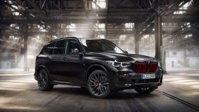 A 2022 BMW X5 Black Vermilion Edition luxury SUV parked in a sun-dappled warehouse