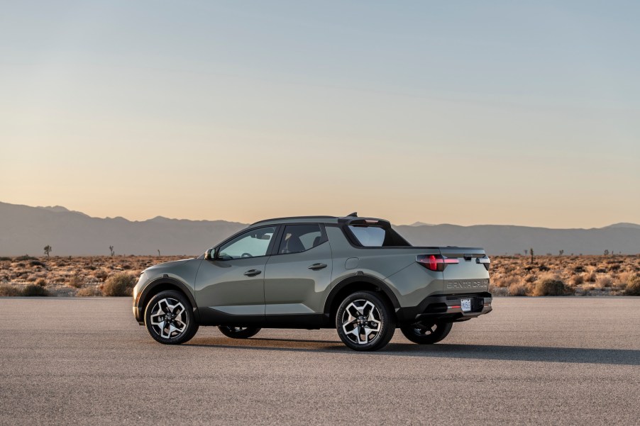 A silver 2022 Hyundai Santa Cruz parked on asphalt in a desert with mountains in the distance