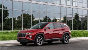 A red metallic 2022 Hyundai Tucson compact SUV parked outside a glass building