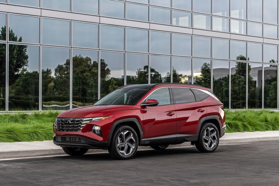 A red metallic 2022 Hyundai Tucson compact SUV parked outside a glass building