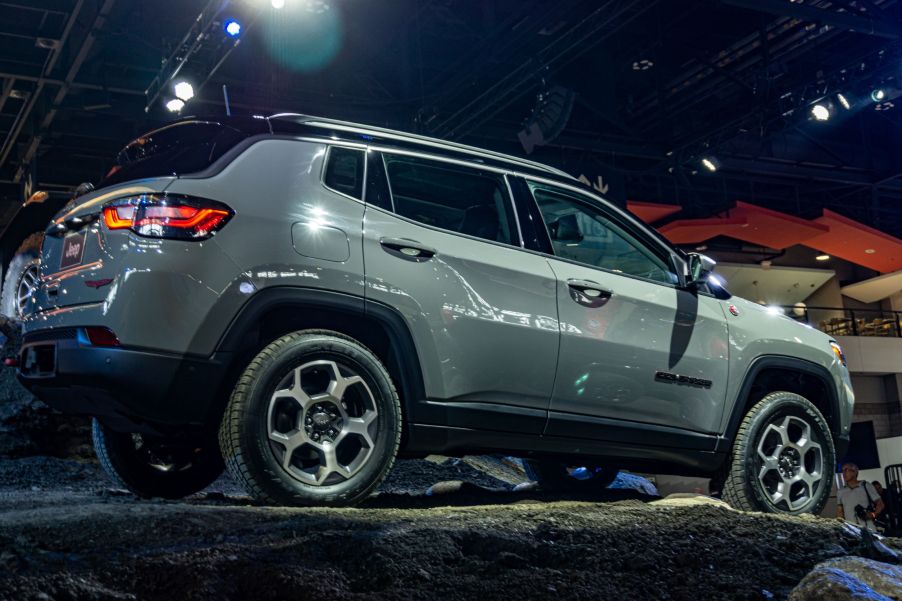 The side 3/4 view of a gray 2022 Jeep Compass Trailhawk on a simulated gravel rise