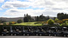 Lines and rows of golf carts parked on a parking lot next to a golf course