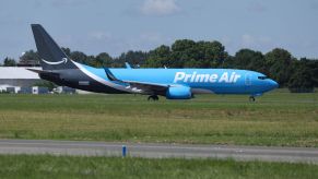 A blue, black, and white Amazon Prime Air Boeing 737 aircraft parked in an air field