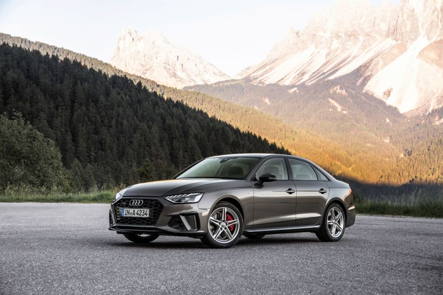 A 2021 Audi A4 Sedan model parked on an asphalt lot near a forest and mountain range